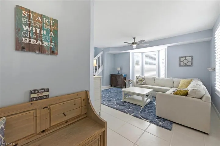 Tiled living area with ceiling fan and baseboards