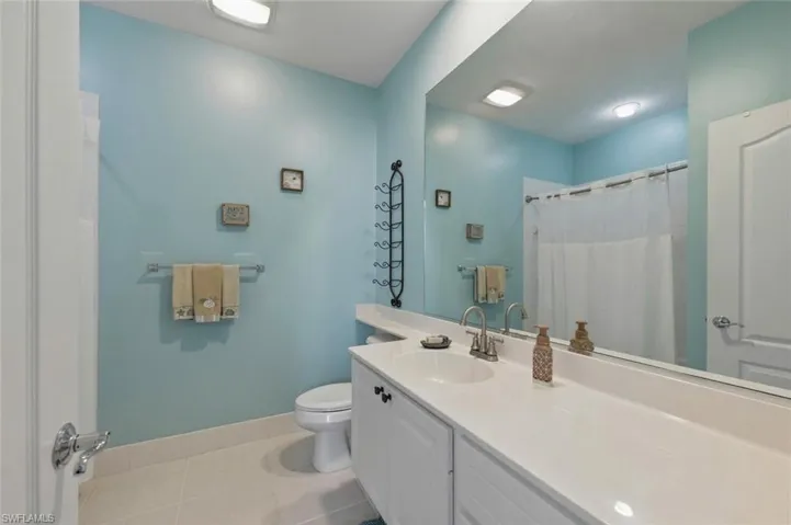 Bathroom with vanity, light tile patterned floors, and a shower with shower curtain