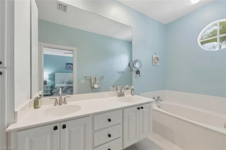 Full bath with double vanity, a garden tub, ensuite bath, and light tile patterned flooring