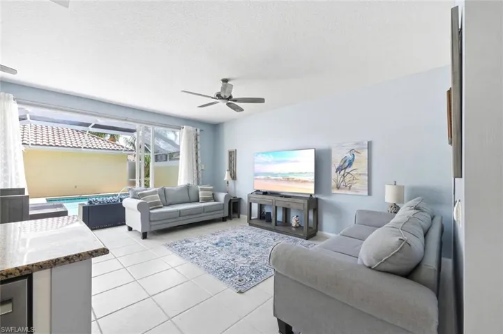 Living area with ceiling fan, light tile patterned floors, and a textured ceiling