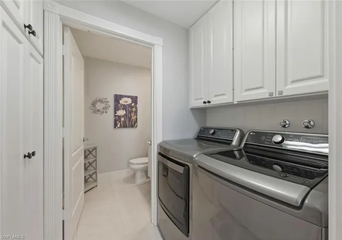 Laundry area with cabinet space, light tile patterned floors, and separate washer and dryer