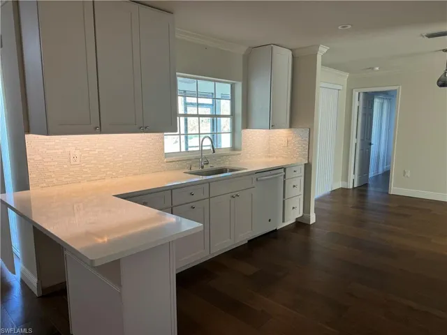 Kitchen featuring dishwasher, dark hardwood / wood-style flooring, sink, and white cabinets