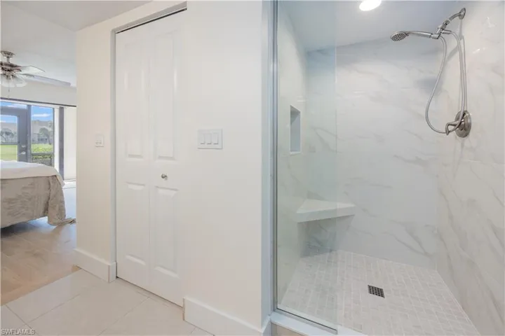 Bathroom featuring ceiling fan, hardwood / wood-style flooring, a tile shower, and french doors