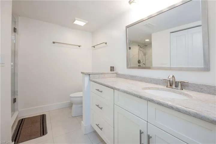Bathroom with vanity, toilet, an enclosed shower, and tile patterned flooring