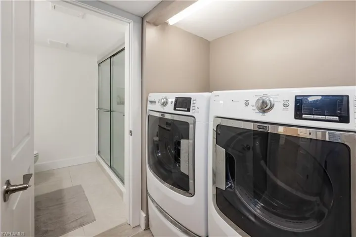Laundry room with washer and clothes dryer and light tile patterned flooring