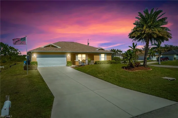 Ranch-style home with a garage, concrete driveway, a yard, and stucco siding