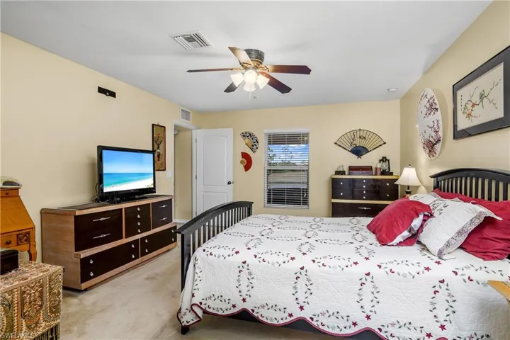 Bedroom featuring a ceiling fan, visible vents, and light colored carpet