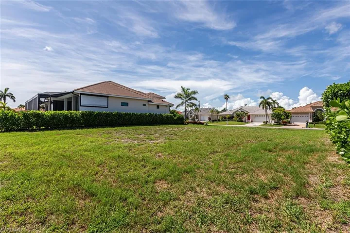 View of green lawn featuring a garage and a residential view