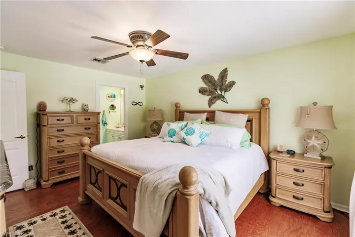 Bedroom with dark wood-type flooring, ensuite bathroom, and ceiling fan