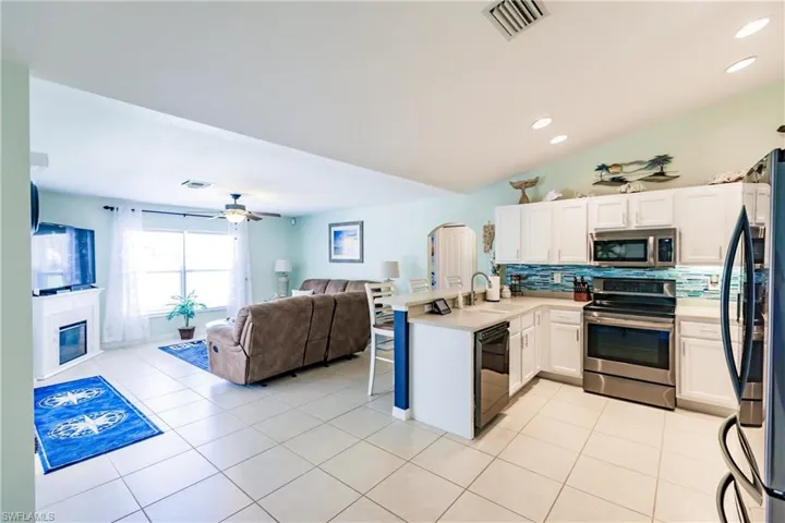 Kitchen with black appliances, sink, tasteful backsplash, ceiling fan, and light tile floors