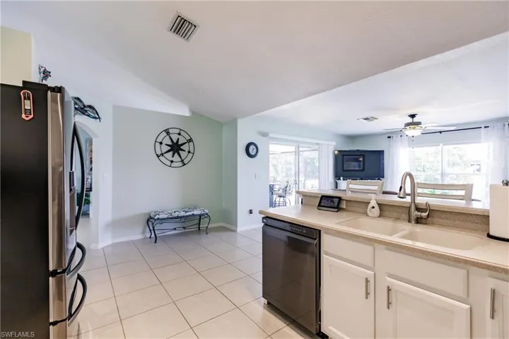 Kitchen featuring stainless steel fridge with ice dispenser, ceiling fan, black dishwasher, white cabinetry, and sink