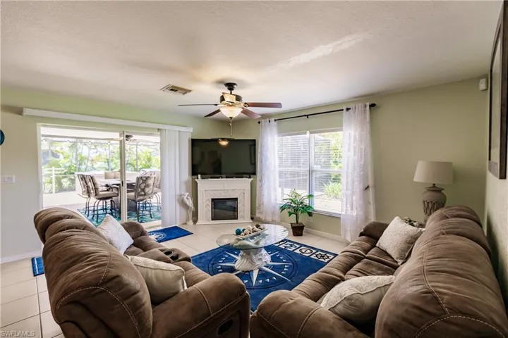 Living room featuring a textured ceiling, ceiling fan, and light tile floors