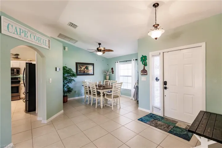 Entrance foyer with lofted ceiling, light tile flooring, and ceiling fan