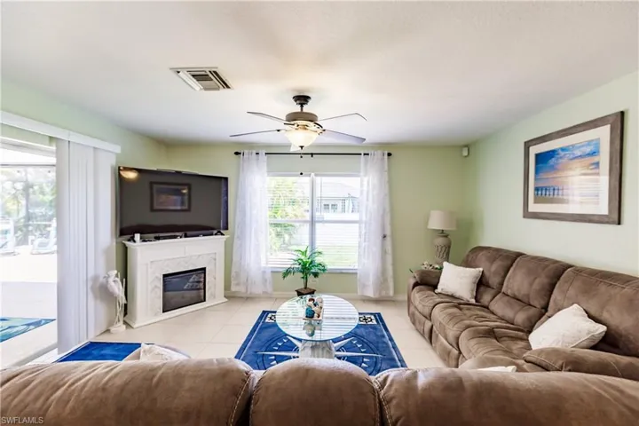 Tiled living room featuring a high end fireplace and ceiling fan