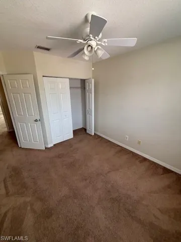 Carpeted interior space featuring a ceiling fan with integrated lighting, bi-fold closet doors, and light-toned walls