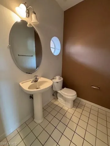 Pedestal sink with an oval mirror and a two-light vanity fixture