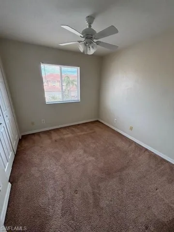 Neutral wall tones, brown carpeting, and a white ceiling fan with integrated lighting