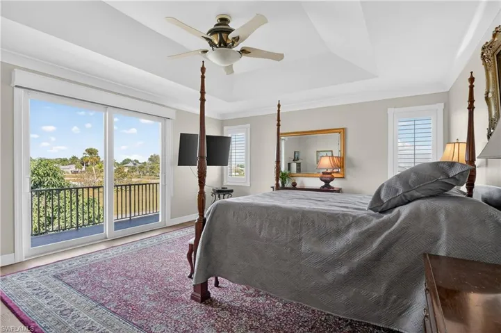 Bedroom with access to exterior, a raised ceiling, and ceiling fan