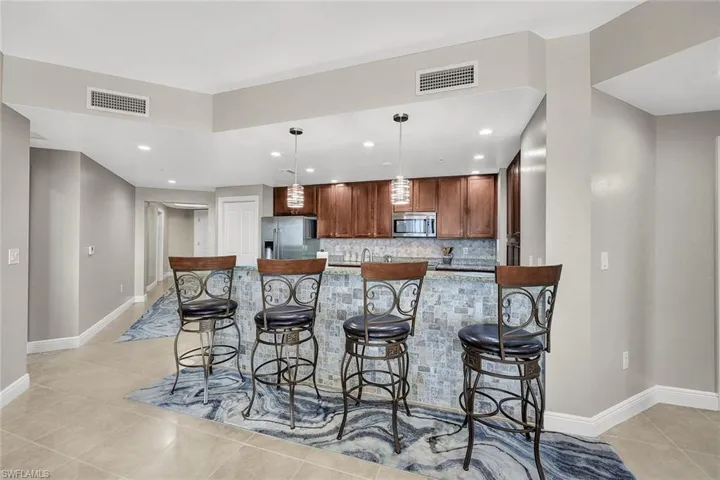 Stone and tile accents, with luminous pendant lights, create perfect bar seating for the kitchen!