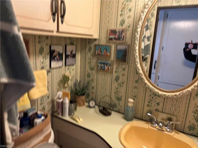 Half bathroom featuring vanity and wallpapered walls