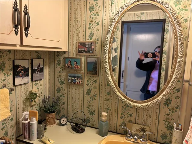 Bathroom with wallpapered walls and vanity