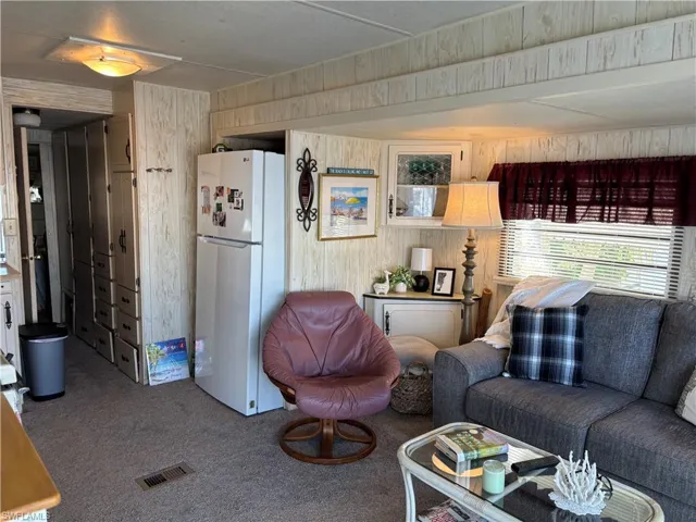 Carpeted living room with wood walls