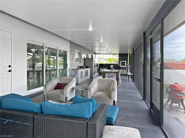 Expansive screened-in lanai featuring a full outdoor kitchen, recessed lighting, and large format tile flooring
