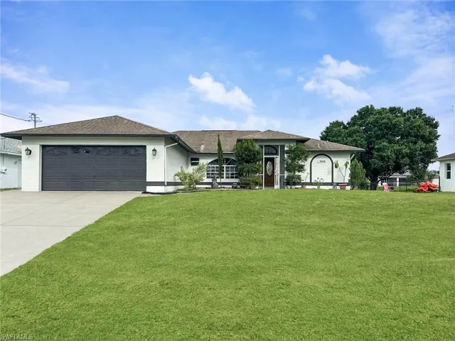 Expansive front lawn, concrete driveway, attached two-car garage, covered entry, and established landscaping