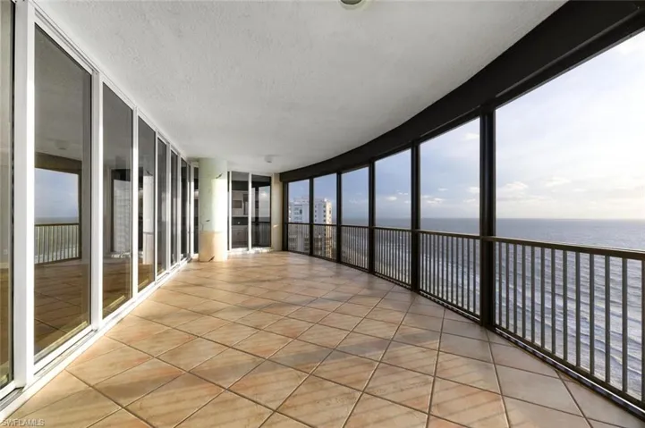 Unfurnished sunroom with floor to ceiling windows, a textured ceiling, tile patterned flooring, and a water view