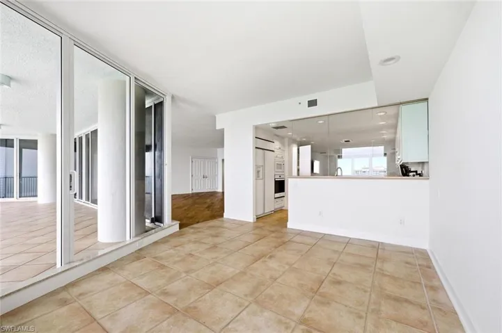 Modern kitchen featuring white cabinetry, granite countertops, tile flooring, and integrated white appliances including a refrigerator, oven, microwave, and dishwasher