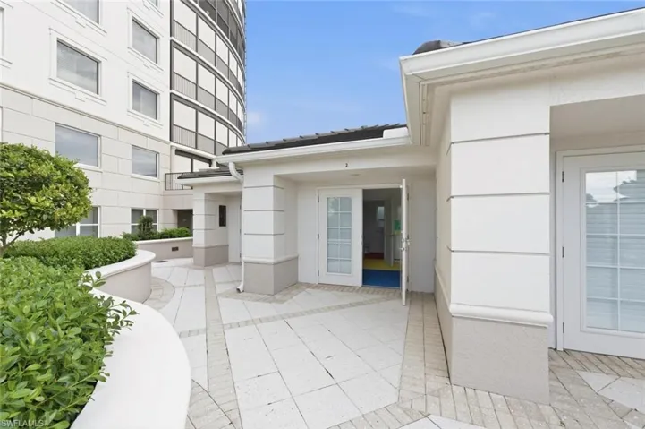 Curved balcony featuring an expansive ocean backdrop, tiled flooring, full-height sliding glass panels, and a dark metal railing