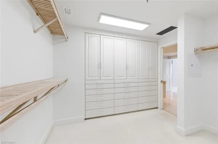 Bathroom featuring a large corner soaking tub, dual vanity sinks with light-toned countertops, extensive wall-mounted mirrors, and recessed ceiling lighting