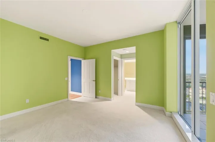 Carpeted empty room with baseboards and a wall of windows
