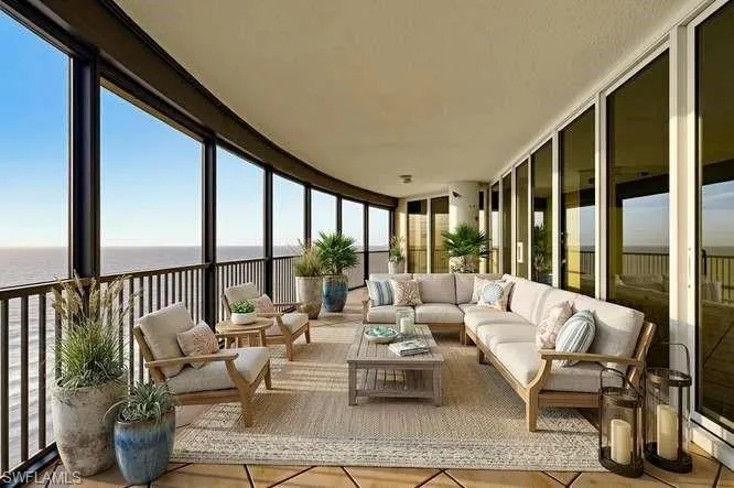 Expansive curved balcony featuring floor-to-ceiling windows, black metal railings, and a textured ceiling