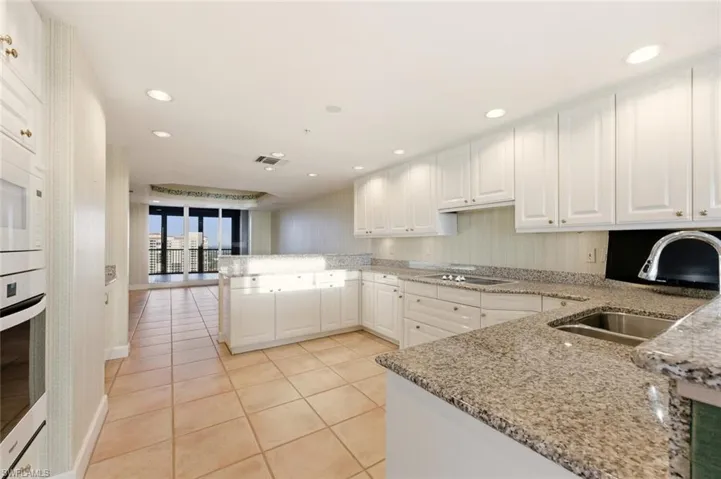 Kitchen featuring white cabinetry, stainless steel oven, a peninsula, light stone countertops, and recessed lighting