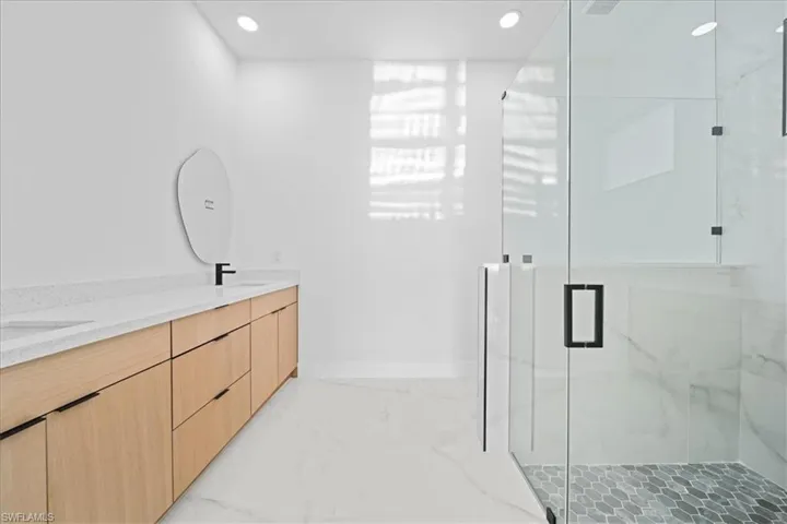 Modern bathroom with a spacious glass-enclosed shower featuring hexagonal tile flooring