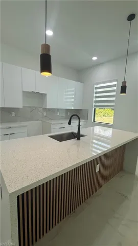 Modern kitchen featuring a large island with a light-toned countertop and slatted wood-finish paneling