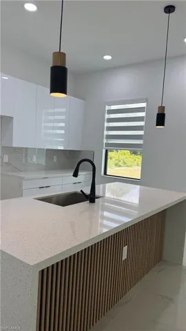 Kitchen island featuring a light-toned countertop with an integrated sink and matte black faucet