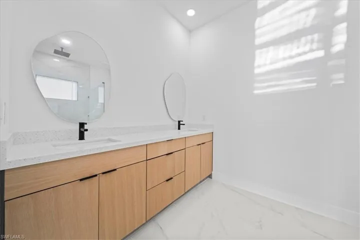 Dual sinks set into a long light wood-finish vanity with a light speckled countertop