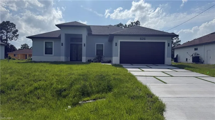 Modern stucco exterior with contrasting trim, a two-car garage, and a contemporary concrete driveway featuring artificial turf accents