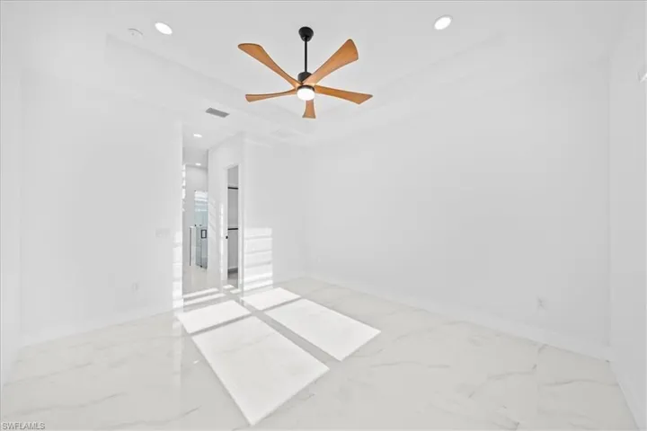 Spacious room featuring a tray ceiling with recessed lighting and a wood-finish ceiling fan