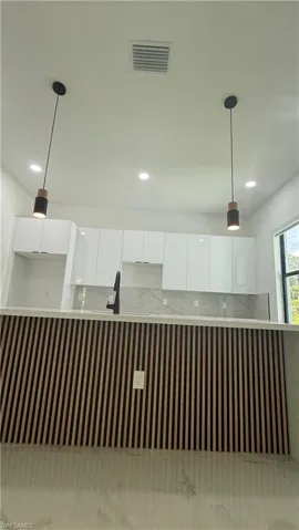 Kitchen island with vertical slat wood-finish paneling, white countertop, and two pendant lights