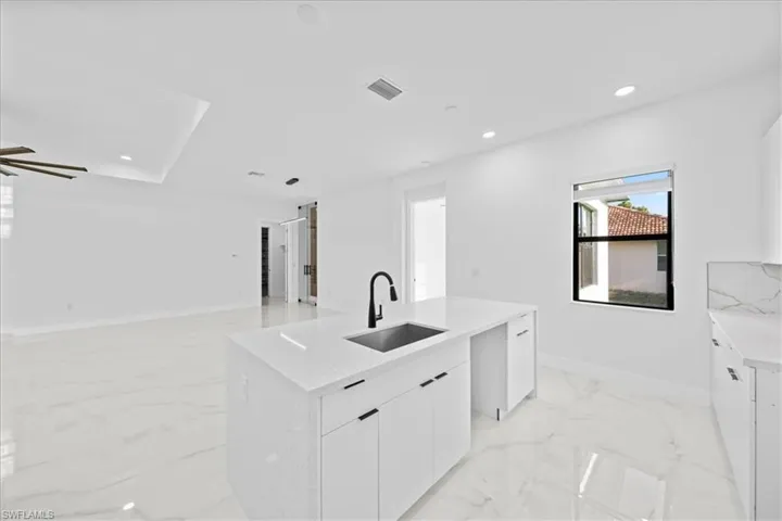 Kitchen island with a stainless steel undermount sink, matte black faucet, and white countertop