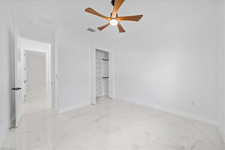Bright room featuring large format tile flooring, a contemporary ceiling fan, and an organized closet with built-in shelving