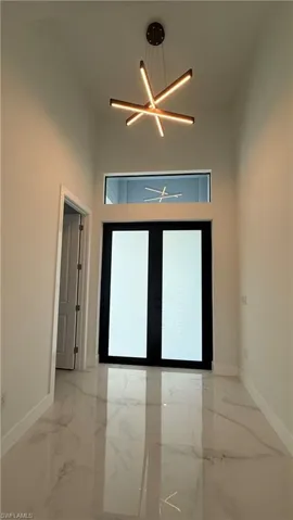 Entryway featuring a modern chandelier, double-door entry with frosted glass, and high ceilings