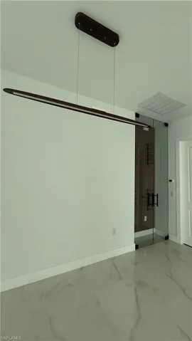 Contemporary linear chandelier illuminating a space with large format porcelain tile flooring