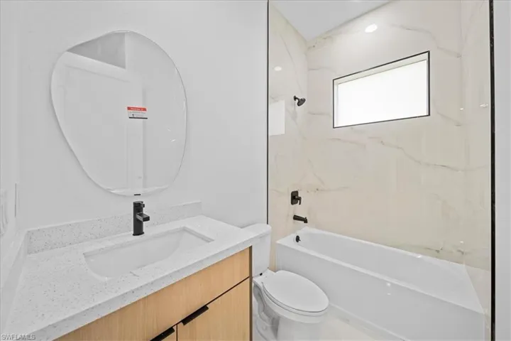 Bathroom with light wood-finish vanity, integrated sink, and speckled countertop