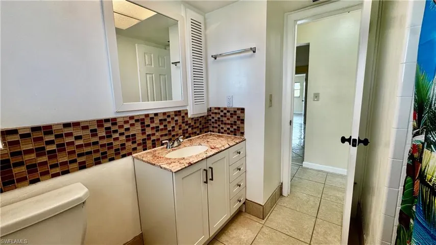 Vanity with granite counter and tile backsplash