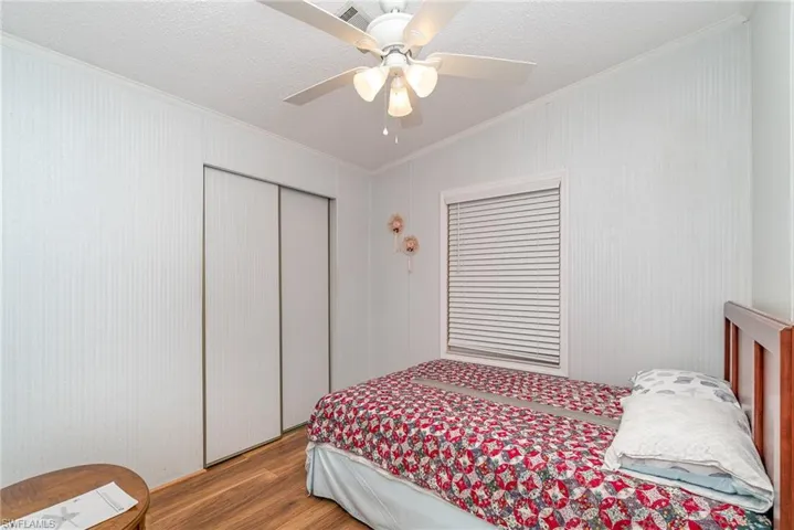 Bedroom with a textured ceiling, ornamental molding, a closet, ceiling fan, and wood-type flooring