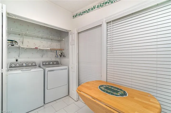 Laundry room featuring washing machine and dryer, a textured ceiling, and light tile patterned flooring